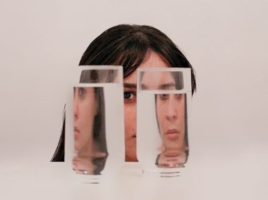 a woman's face distorted through two clear glasses of water