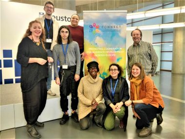 A group of people standing in front of a banner that has text describing the Connect project, an initiative for audience development across Europe, sharing knowleding and promoting cooperation.