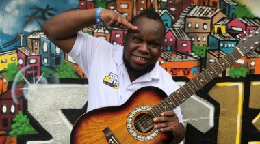 Founder of Son Bata saluting the camera with a guitar in hand