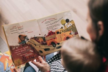 Looking over the shoulder of an adult and a child reading a book in a non-English language