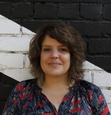 Genevieve Grieves wearing a red and blue printed shirt against a background painted black and white