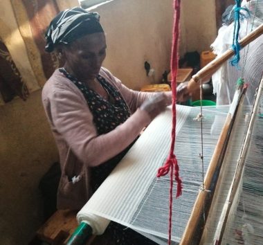 An employee demonstrates her weaving skills