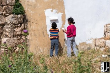 Two children painting a wall white